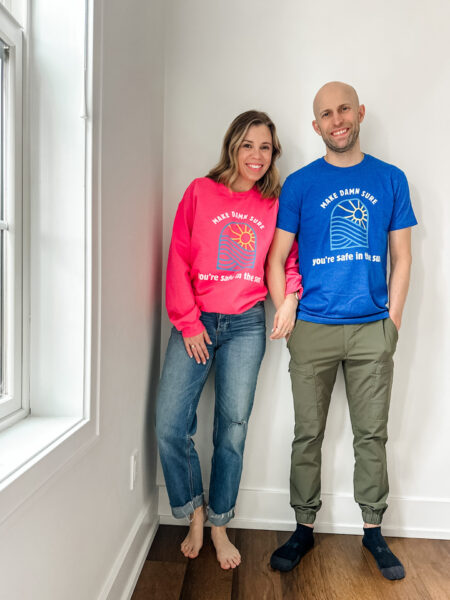 Leah und ihr Mann tragen T-Shirts, die sie für ihre Spendenaktion „Save Destination Healthy Skin“ entworfen hat.